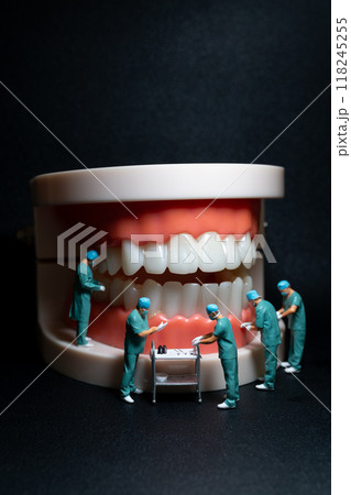 Miniature figurines of surgeons working on a large model of human teeth Miniature figurines of surgeons working on a large model of human teeth 118245255