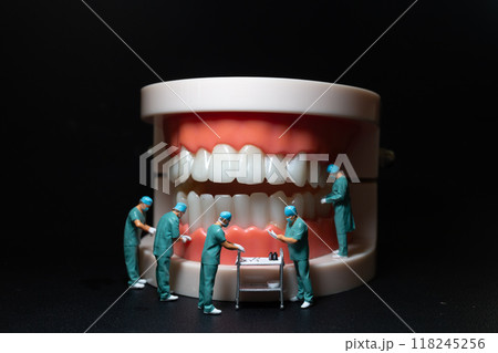 Miniature figurines of surgeons working on a large model of human teeth 118245256
