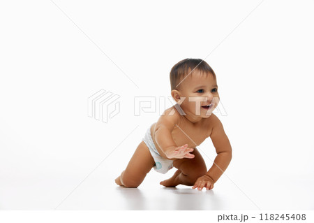 Little happy baby girl, toddler in diaper crawling cheerfully on bed isolated on white studio background. Exploring and playing Little happy baby girl, toddler in diaper crawling cheerfully on bed isolated on white studio background. Exploring and playing 118245408