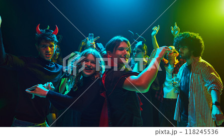 Lively Halloween party scene at nightclub with young people,be friends in costumes and makeup, celebrating holiday with fun and joy, laughing and dancing. 118245536