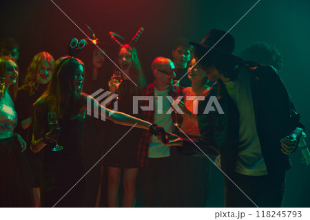 Invitation for a dance. Halloween party scene with young people dressed as ghosts, witches, and vampires. Cheerful celebration, laugh and joy Invitation for a dance. Halloween party scene with young people dressed as ghosts, witches, and vampires. Cheerful celebration, laugh and joy 118245793