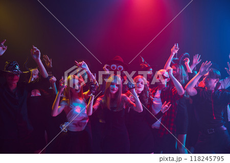 Costumed friends, boys and girls, attending Halloween party, celebrating with non-alcoholic drinks and treats, dancing and laughing. Night club event 118245795