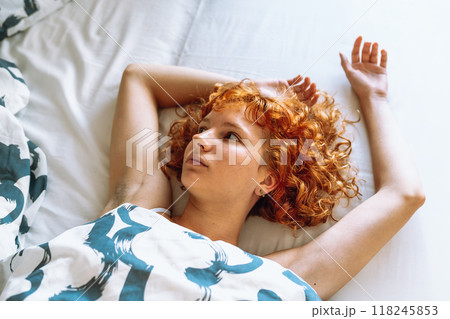 young attractive redhead curly woman waking up with pleasure stretching lying in bed young attractive redhead curly woman waking up with pleasure stretching lying in bed 118245853