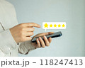 A woman is holding a cell phone and pointing to a five star rating 118247413