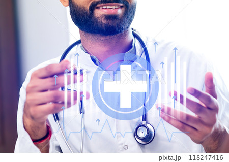 A man wearing a white lab coat is holding a stethoscope and smiling 118247416