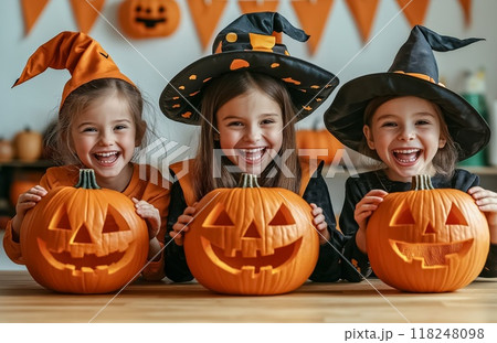 Three little girls in witches costumes holding carved pumpkins for halloween 118248098