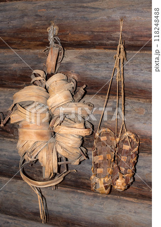 Woven bast shoes hang on the wall. Pairs of woven shoes Woven bast shoes hang on the wall. Pairs of woven shoes 118248488