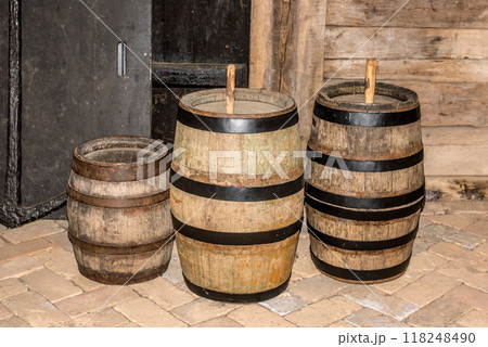 Three old wooden barrels against a wooden wall Three old wooden barrels against a wooden wall 118248490