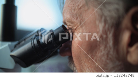 Close up of mature microbiologist conducting fossil analysis under microscope Close up of mature microbiologist conducting fossil analysis under microscope 118248749