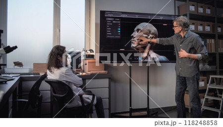 Male and female archaeologists work with 3D visualization of ancient human head anatomy Male and female archaeologists work with 3D visualization of ancient human head anatomy 118248858