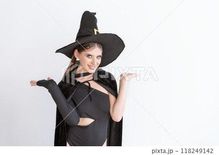 Happy smiling woman in black hat and clothing. Space for text. White background. Black Friday. Halloween party. 118249142