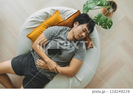 Man sleep over the phone on the bean bag sofa, taking a nap in the afternoon. 118249229