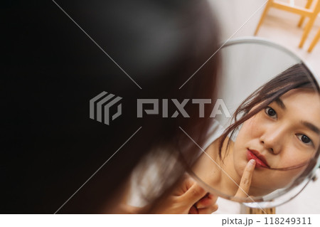 Woman using mirror for wearing make up. 118249311