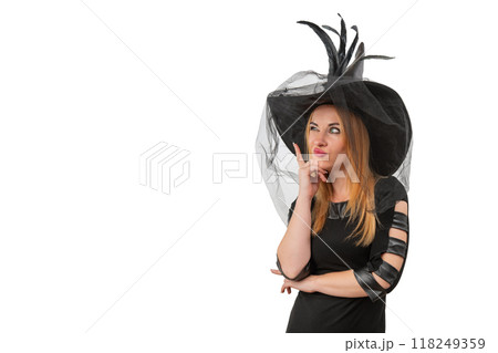 Thoughtful beautiful girl in black witch hat makes a decision. Halloween costume, white background, space for text Thoughtful beautiful girl in black witch hat makes a decision. Halloween costume, white background, space for text 118249359