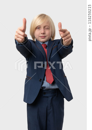Portrait of a little boy with blond hair in a suit and tie and points at the camera Portrait of a little boy with blond hair in a suit and tie and points at the camera 118250215