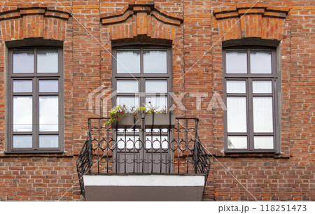 Beautiful flower box on a balcony with green plants and flowers in an old brick house 118251473