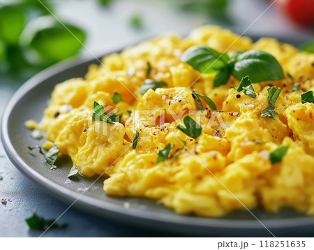 Close-up of a perfectly scrambled eggs dish, garnished with herbs on a plate.  118251635