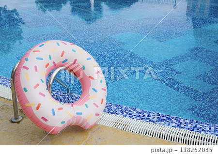 A large beautiful inflatable swimming lap stands at the edge of a pool filled with clear water on a sunny day. 118252035
