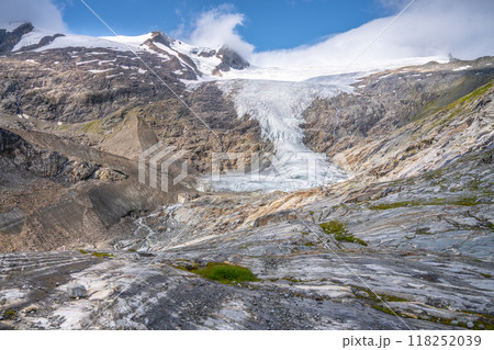 The majestic Schlaten Glacier extends down the mountainside, surrounded by rocky terrain and snowcapped peaks under a vibrant blue sky. The majestic Schlaten Glacier extends down the mountainside, surrounded by rocky terrain and snowcapped peaks under a vibrant blue sky. 118252039