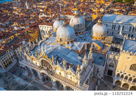 The stunning St Marks Basilica stands proudly in Piazza San Marco, showcasing its intricate architecture and domes against a vibrant sunset in Venice, attracting visitors and capturing hearts. The stunning St Marks Basilica stands proudly in Piazza San Marco, showcasing its intricate architecture and domes against a vibrant sunset in Venice, attracting visitors and capturing hearts. 118252224
