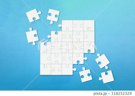 角がバラバラに欠けた青い背景の白いジグソーパズル 角がバラバラに欠けた青い背景の白いジグソーパズル 118252329