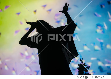 Beautiful female singer silhouette sings on stage in light show Beautiful female singer silhouette sings on stage in light show 118252465