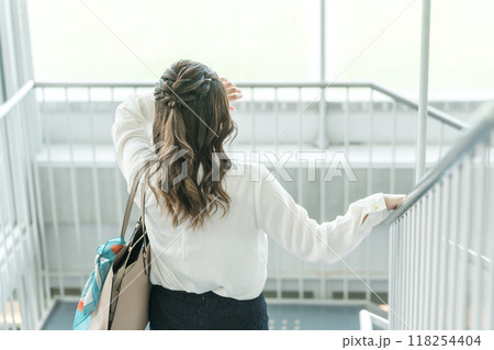 階段を降りる体調不良の若いビジネスウーマン(頭痛・疲労・過労) 階段を降りる体調不良の若いビジネスウーマン(頭痛・疲労・過労) 118254404
