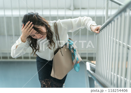 階段で体調不良になりうずくまるビジネスウーマン（貧血・立ちくらみ・目眩） 118254406