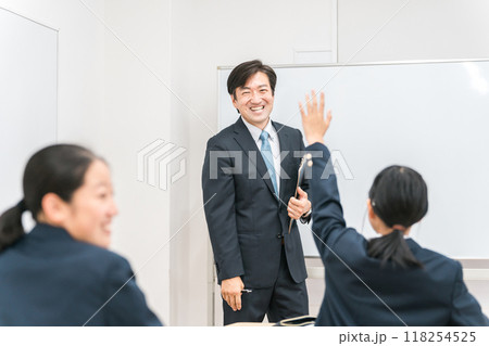 塾・学校の教室で中学生・高校生に勉強を教える男性講師・教師 118254525