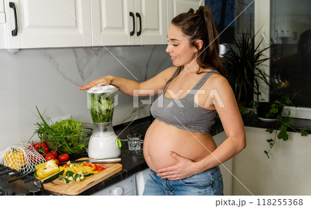 Young pregnant woman drinking healthy green smoothie at home. Young pregnant woman drinking healthy green smoothie at home. 118255368