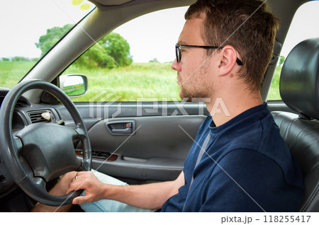 Young adult man driving the car and looking at road Young adult man driving the car and looking at road 118255417
