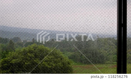 雨の日の風景、室内から外を眺める、雨粒で濡れる窓ガラス 118256276