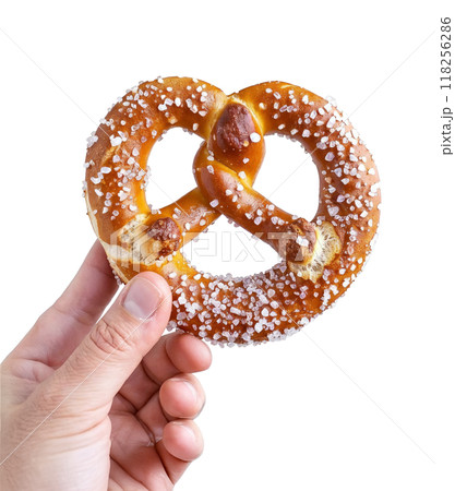 A hand holding a freshly baked German pretzel with coarse salt isolated on a transparent background. A hand holding a freshly baked German pretzel with coarse salt isolated on a transparent background. 118256286