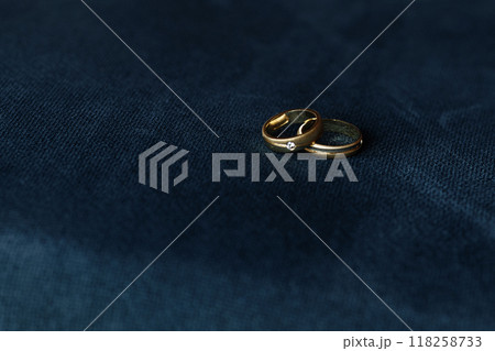 Two gold wedding rings are on a blue cloth 118258733