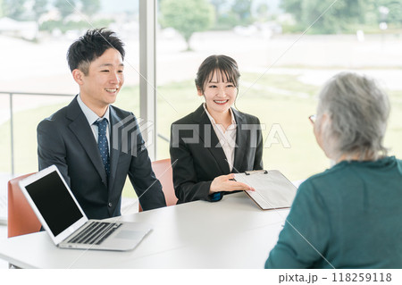 シニア女性に書類の説明をするビジネスウーマンとビジネスマン 118259118