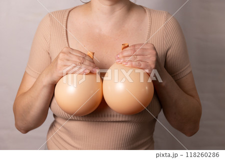 a woman holding balloons in her hands symbolizes plastic surgery for breast augmentation 118260286