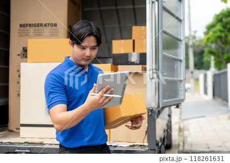 An Asian delivery guy checking the address on his tablet while carrying a package for delivery. 118261631