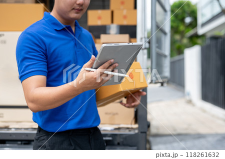 A delivery guy checking the address on his tablet while carrying a package for delivery. 118261632