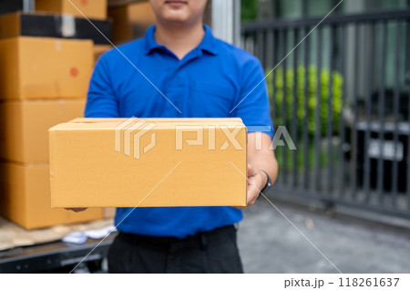 A cropped image of a delivery guy standing at the back of his truck, carrying a package for delivery 118261637