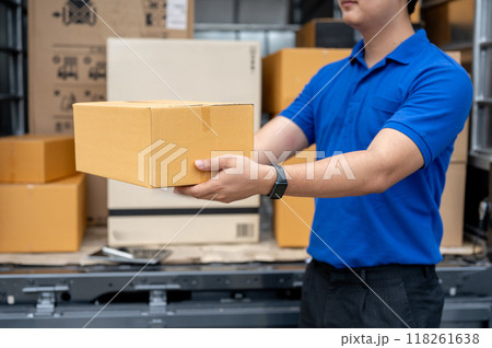 A cropped image of a delivery guy standing at the back of his truck, carrying a package for delivery 118261638