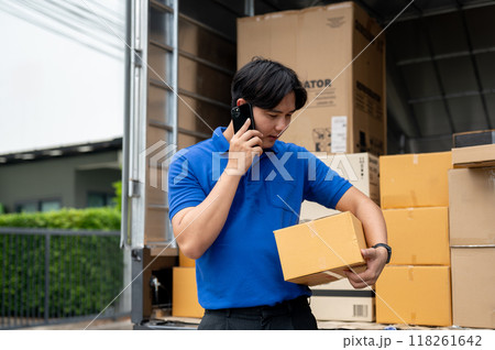 A delivery guy is carrying a package and calling a customer to pick it up in front of their house. A delivery guy is carrying a package and calling a customer to pick it up in front of their house. 118261642