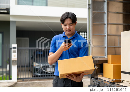 A delivery guy is taking a picture of a package before delivering it in front of a customer's house. 118261645