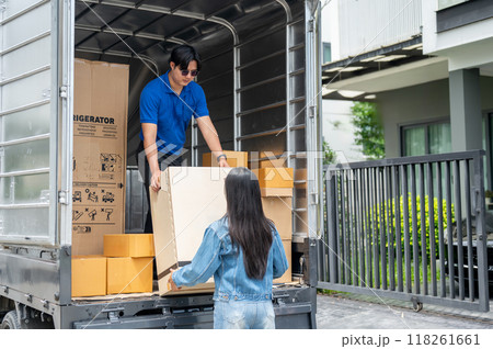 An Asian delivery man is unloading a cardboard box from his truck with his female assistant. 118261661