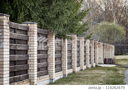 A fence made of bricks and boards A fence made of bricks and boards 118262670
