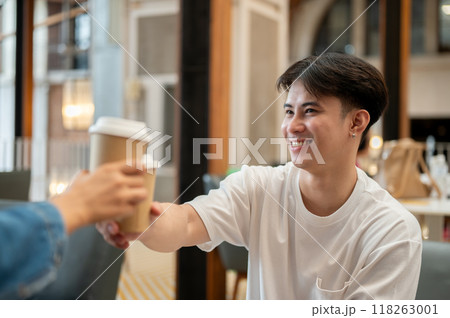 A happy Asian man enjoying drinking coffee with his friend during a meeting at a coffee shop. 118263001