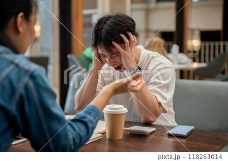 A stressed Asian man is expressing frustration and a headache, screaming while discussing work. 118263014
