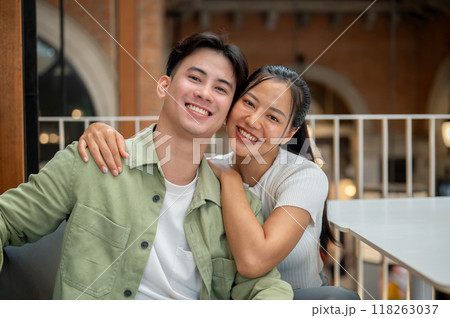 A lovely, happy young Asian couple is taking a selfie together while on a date at a coffee shop. A lovely, happy young Asian couple is taking a selfie together while on a date at a coffee shop. 118263037
