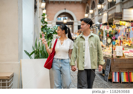 A lovely Asian couple are enjoying their time together as they walk through a market on a date. A lovely Asian couple are enjoying their time together as they walk through a market on a date. 118263088