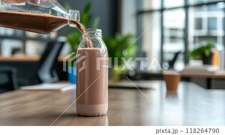 Pouring Chocolate Milk into Bottle on Wooden Table in Modern Office 118264790