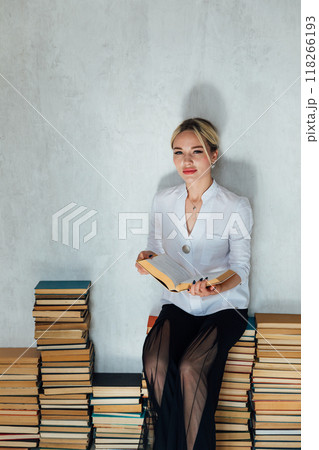 Beautiful woman reading book and stacks of books in library Beautiful woman reading book and stacks of books in library 118266193